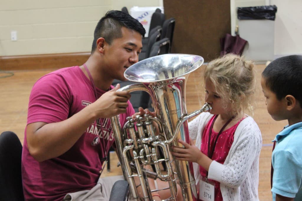 Kim McCaskill teaching children how to play brass instrument at music camp